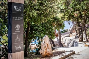 Ein Wegweiser mit Restaurantnamen, darunter 'On the Rocks', 'Neptun Terrace', 'Vesta' und 'Blue Pig'.