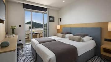 Habitación de hotel con dos camas, un escritorio, una silla, una lámpara y vistas al exterior.