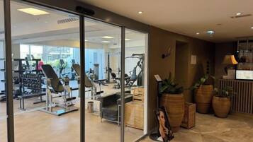 Un gimnasio con equipo de ejercicio, un mostrador de recepción y plantas en macetas.