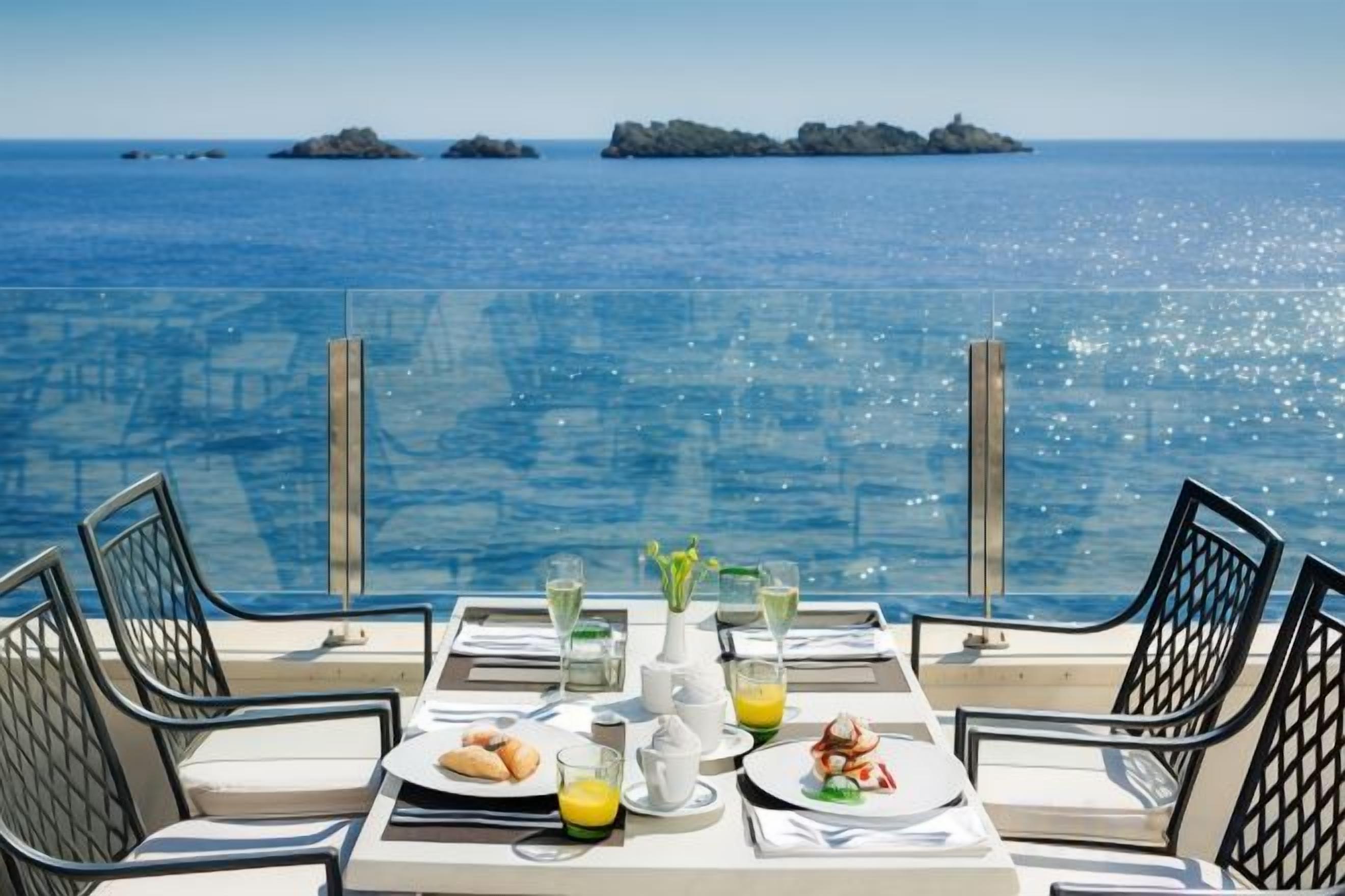 Une table dressée pour le petit-déjeuner, avec vue sur la mer et les îles.
