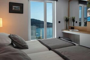 Una camera d'albergo con un letto, una scrivania e un'ampia finestra vista mare.