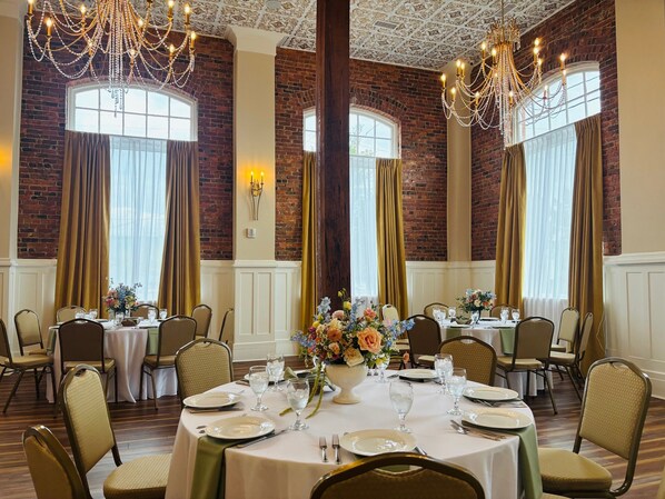 A dining area with brick walls, chandeliers, and tables set for a meal.