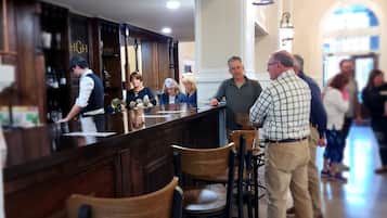 Zona de bar amb tamborets de fusta i un barman.