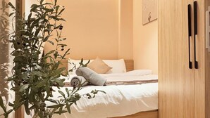 Un dormitorio pequeño y ordenado, con una cama, una planta en maceta y un armario de madera.