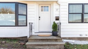 A house with a white front door, number 17, and a small potted plant on the steps.