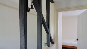Een kamer met een bed, een houten vloer en een witte muur.