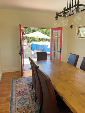 An open dining area with a wooden table, leather chairs, and a patterned rug.