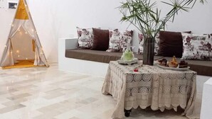 Um quarto aconchegante com um sofá, uma mesa com toalha de renda e um vaso de planta.