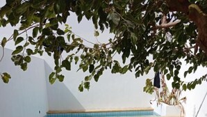 Uma área de refeições ao ar livre com uma piscina ao fundo.
