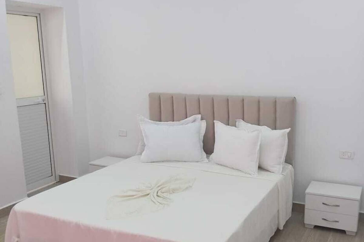 A bedroom with a bed, bedside tables, and an air conditioning unit.