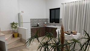 Cozinha moderna com fogão embutido, janela e espaço de refeições com mesa posta para dois.