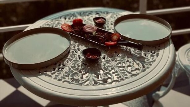 A table with two bowls and a decorative tray on a balcony with a mountain view. - Roots Munnar (Devikolam)