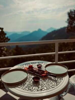 Un tavolo con due ciotole e un vassoio decorativo su un balcone con vista sulle montagne.