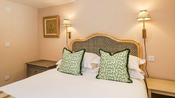 A bedroom with a large bed, two bedside lamps, a framed picture on the wall, and a nightstand. - Cedar (Newbury)