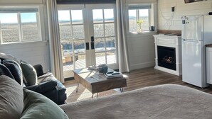 Una habitación amplia con una cama grande, chimenea, una mesa de comedor y una zona de cocina.