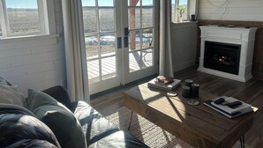 Una sala de estar acogedora con chimenea, un ventanal con vistas al desierto y un espacio de estar confortable.