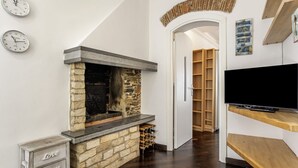 Una sala de estar moderna con una chimenea de piedra, un televisor sobre un mueble de madera y una vinoteca.
