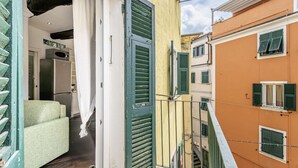 Un callejón estrecho con una puerta verde, una cortina blanca y una escalera que lleva a un edificio naranja.
