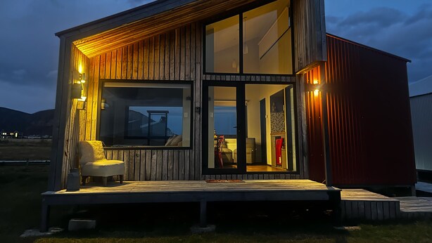 Una cabaña moderna de madera con ventanas grandes y una terraza.