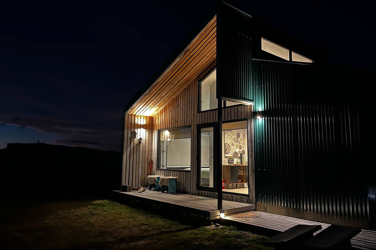 A modern house with a wooden exterior, large windows, and a deck area.