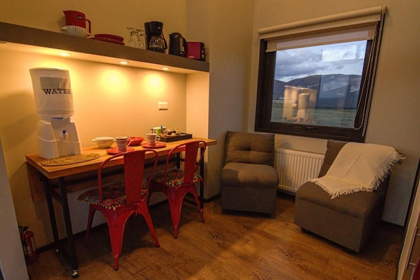 Un espacio habitable compacto con comedor, dispensador de agua, ventana con vistas y una zona de estar acogedora.