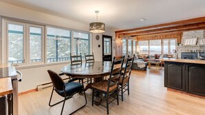 A spacious kitchen with a dining area, large windows, and a fireplace.