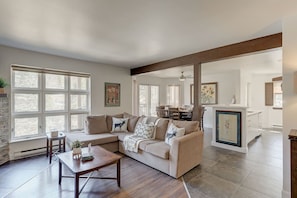 A spacious living room with a large sectional sofa, a wooden coffee table, and a dining area with a table and chairs.