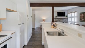 Eine moderne Küche mit weißen Schränken, einem eingebauten Backofen und einer großen Kochinsel mit Spüle.