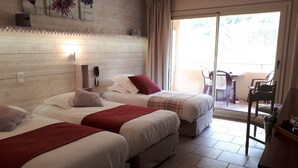 A hotel room with two beds, a sliding glass door to the balcony, and a wooden headboard. - Logis Hotel Le Mont Barral (Châtillon-en-Diois)