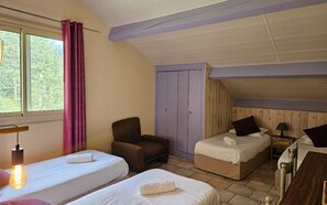 A room with two beds, a chair, a wardrobe, and a window with curtains. - Logis Hotel Le Mont Barral (Châtillon-en-Diois)