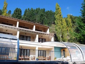 A multi-story hotel with balconies, outdoor seating, and a view of trees and hills. - Logis Hotel Le Mont Barral (Châtillon-en-Diois)