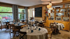 A cozy restaurant with round tables, wooden chairs, and a chalkboard menu. - Logis Hotel Le Mont Barral (Châtillon-en-Diois)