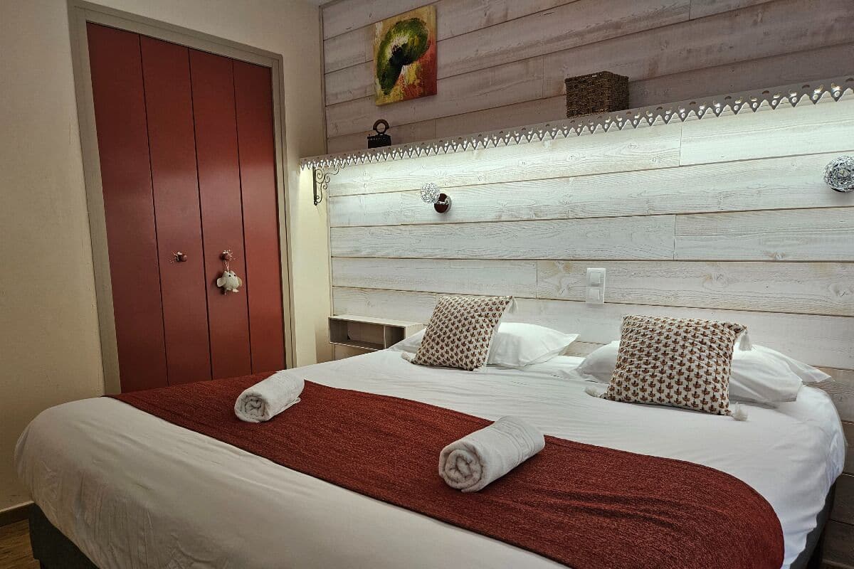 A hotel room with a large bed, a red wardrobe, and a wooden headboard.