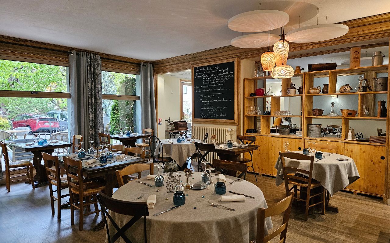 Un restaurante acogedor con mesas redondas, sillas de madera y un menú en una pizarra.