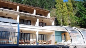 A multi-story hotel with balconies, outdoor seating, and a view of trees and hills. - Logis Hotel Le Mont Barral (Châtillon-en-Diois)