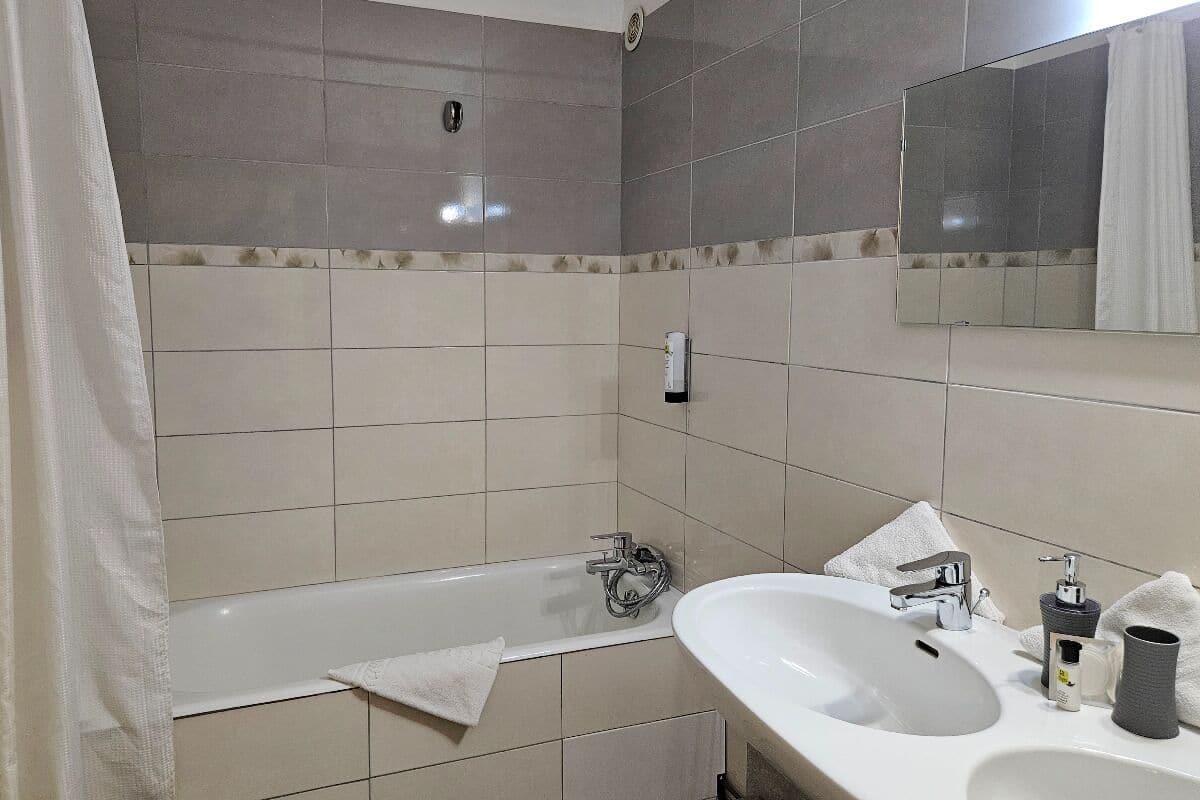 A bathroom with a bathtub, a sink, a mirror, and a towel.