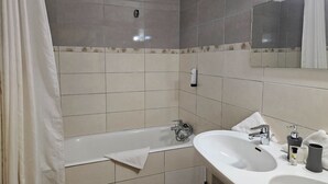 A bathroom with a bathtub, a sink, a mirror, and a towel. - Logis Hotel Le Mont Barral (Châtillon-en-Diois)