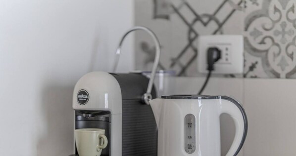 Une machine à café, une tasse et une bouilloire sur un plan de travail.
