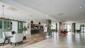 Eine großzügige Lobby mit Holzboden, grünen Wänden und einer Bar.