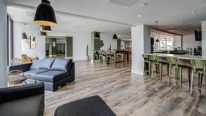 Ein modernes Interieur mit grauem Sofa, Holzboden und grünen Stühlen in einem Essbereich.