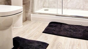 Une salle de bain moderne équipée de toilettes, d’un lavabo et d’une douche à parois de verre.