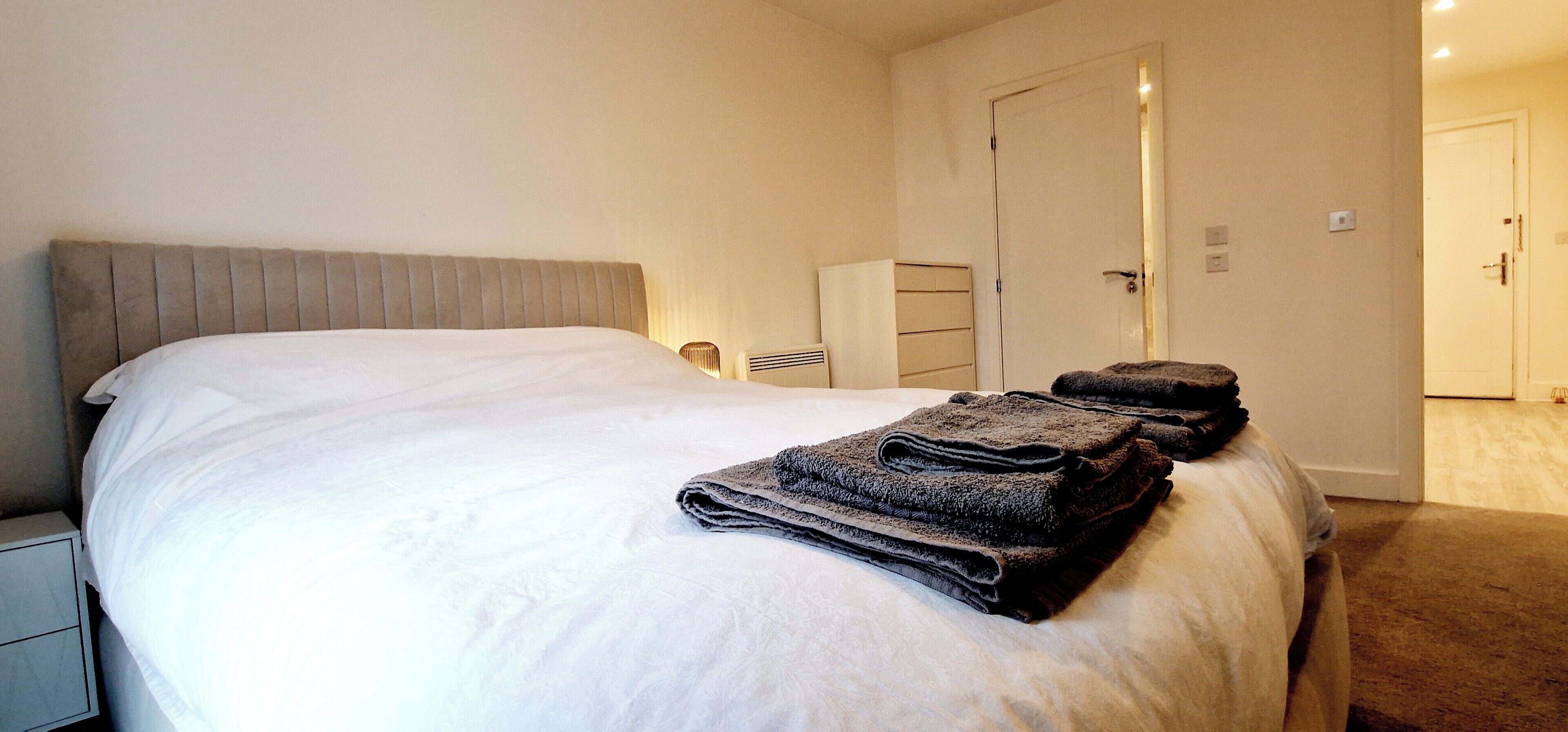 A hotel room with a bed, a nightstand, a wardrobe, and a door.