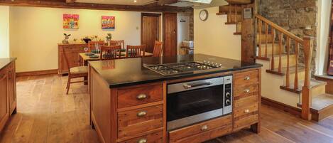 Una cocina con isla central, armarios de madera, horno empotrado y estufa.