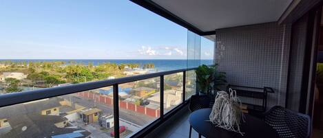 A balcony with a view of the ocean and a cityscape.