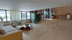 A modern living room with a sofa set, a coffee table, and a staircase leading to an upper level.