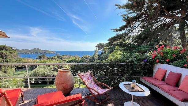 A wooden deck with outdoor furniture, a large vase, and a scenic view of the sea and hills. - Villa 5 rooms with pool near the sea (Hyères)