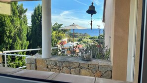 A balcony with a stone ledge, a hanging bell, and a view of the ocean. - Villa 5 rooms with pool near the sea (Hyères)