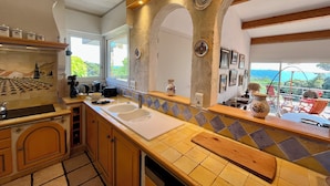 A kitchen with a large window, a sink, and a countertop with a cutting board. - Villa 5 rooms with pool near the sea (Hyères)