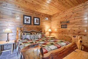 A wooden cabin room with a bed, two nightstands, and a wooden headboard. - Timber View | Hocking Hills, Pool, Lodge, Pets (Rockbridge)