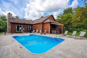 Eine Holzhütte mit Schwimmbad, Sitzgelegenheiten im Freien und einem Steinkamin.